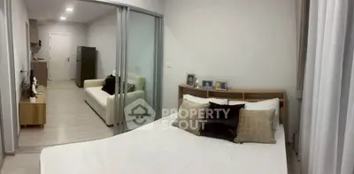 Modern bedroom with sliding glass doors and cozy living area in stylish apartment.