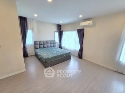 Spacious bedroom with modern decor and large windows for natural light.