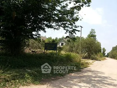 Rural road with greenery and distant house, ideal for serene living.