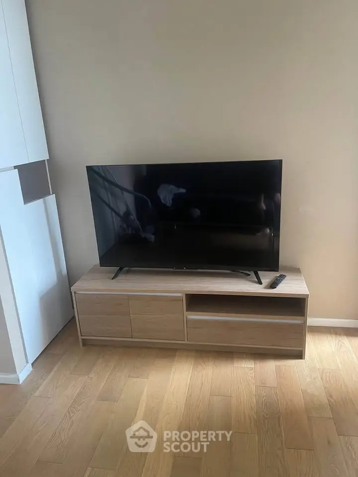 Modern living room with sleek TV stand and flat-screen TV on wooden flooring.