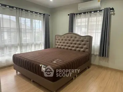 Spacious bedroom with elegant bed and natural light from large windows.