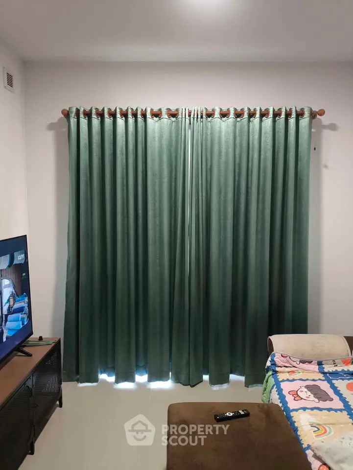 Cozy living room with green curtains and TV setup, perfect for relaxation.