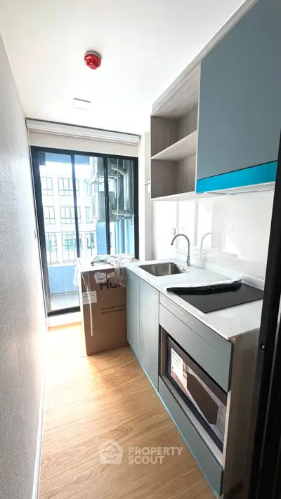 Modern kitchen with sleek cabinetry and large window offering natural light and city view.