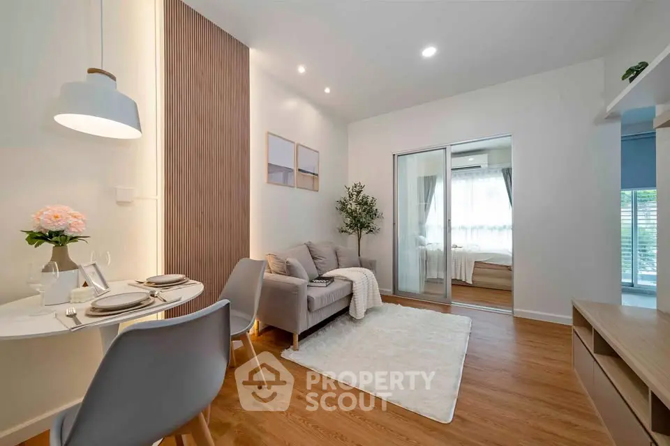 Modern living room with cozy dining area and view into a bright bedroom.