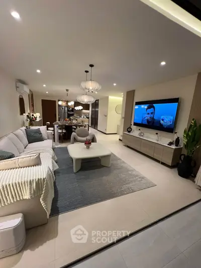 Spacious modern living room with elegant decor and large TV, perfect for relaxation and entertainment.
