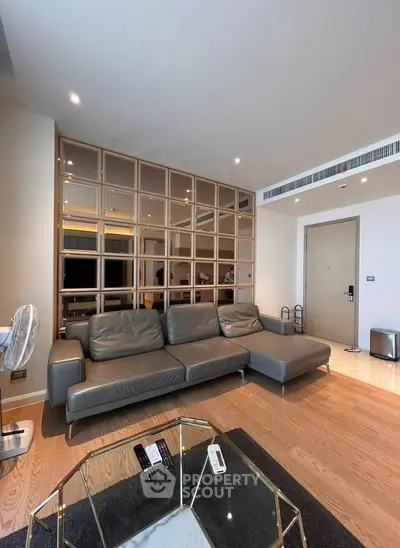Modern living room with sleek gray sofa and stylish partition wall in upscale apartment.