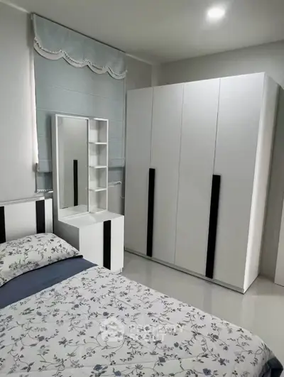 Modern bedroom with floral bedding and sleek white furniture, featuring a spacious wardrobe and vanity mirror.