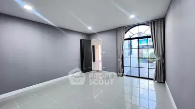 Spacious modern room with large arched window and sleek tile flooring, perfect for customization.