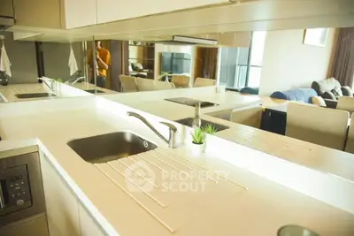 Modern kitchen with sleek design and open layout overlooking a stylish living room.