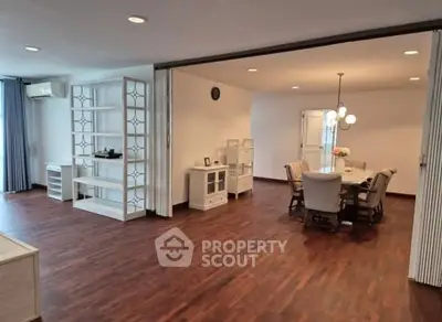 Spacious open-plan living and dining area with elegant wood flooring and modern decor.