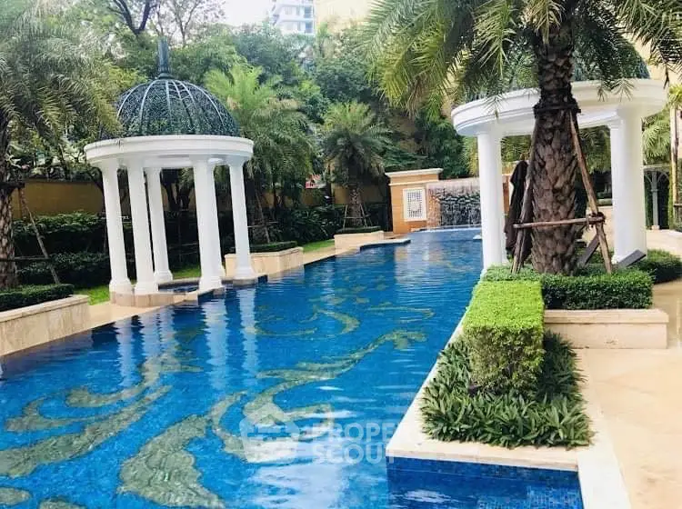 Luxurious outdoor pool with elegant white columns and lush greenery