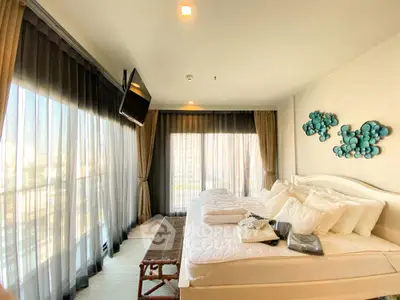 Luxurious bedroom with large windows and modern decor in a high-rise apartment.
