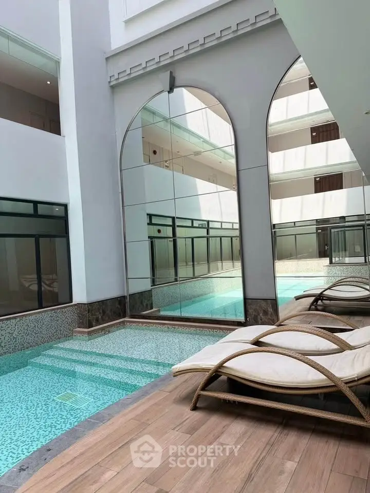 Luxurious indoor pool area with elegant lounge chairs and modern architectural design.