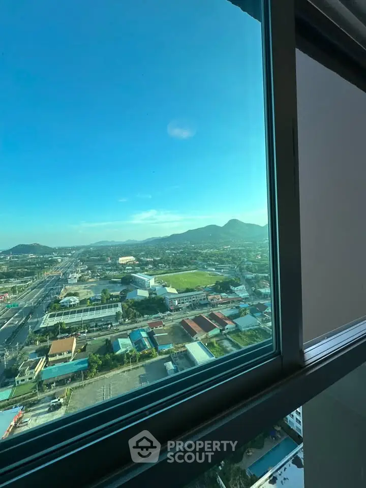 Stunning panoramic view from high-rise window showcasing cityscape and mountains.
