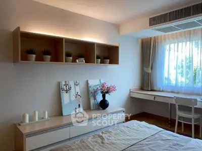 Modern bedroom with stylish decor and natural light, featuring a cozy workspace and elegant wall art.