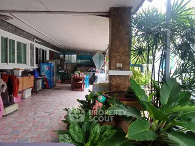 Spacious covered patio with lush greenery and cozy seating area, perfect for relaxation and entertaining.