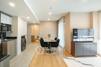 Modern open-plan living room with dining area and kitchen, featuring sleek furniture and appliances.