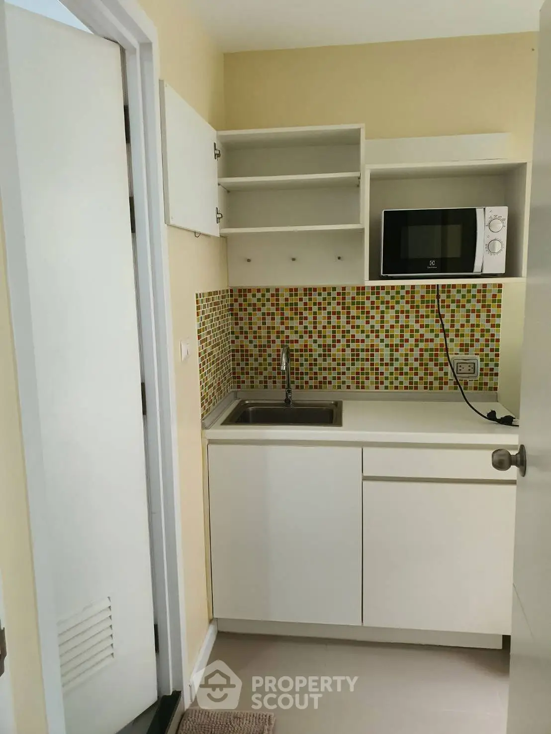 Compact kitchen with modern microwave and colorful backsplash tiles