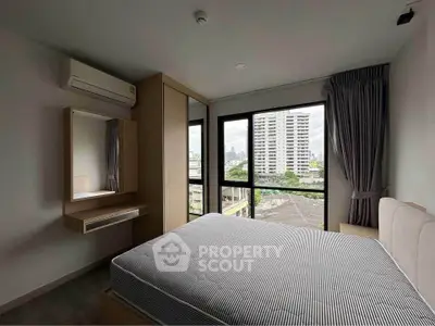 Modern bedroom with large windows and city view, featuring a comfortable bed and built-in wardrobe.