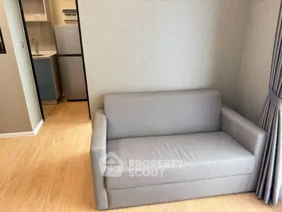 Modern apartment interior with cozy gray sofa and compact kitchen area.