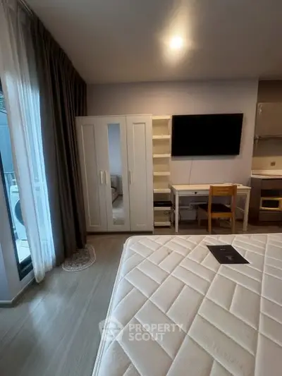 Modern bedroom with balcony access, featuring a sleek wardrobe and wall-mounted TV.