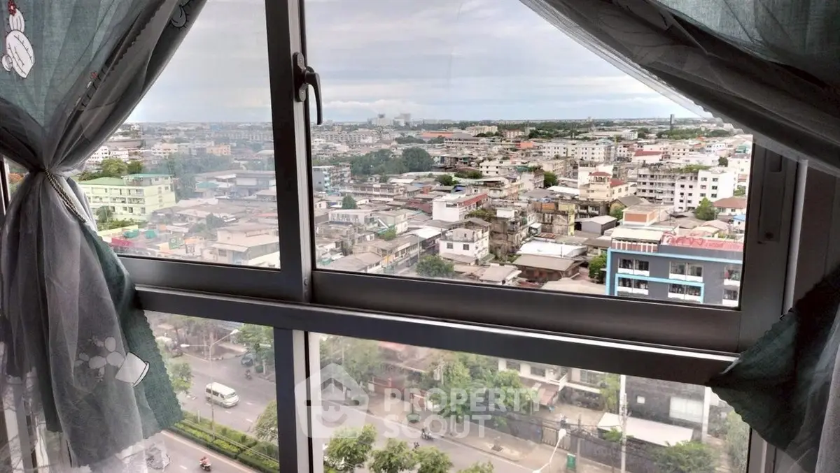 Stunning cityscape view from high-rise apartment window with curtains framing the urban landscape.