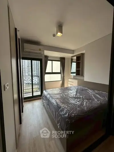 Modern bedroom with large window and city view, featuring sleek design and natural light.