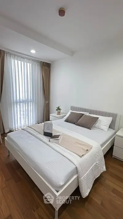 Modern bedroom with cozy decor and large window offering natural light