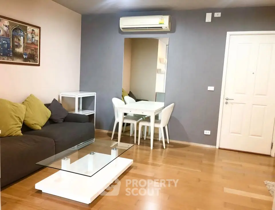 Modern living room with wooden flooring, stylish sofa, and dining area in open layout.