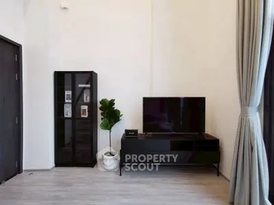 Modern living room with sleek black furniture and large TV setup.