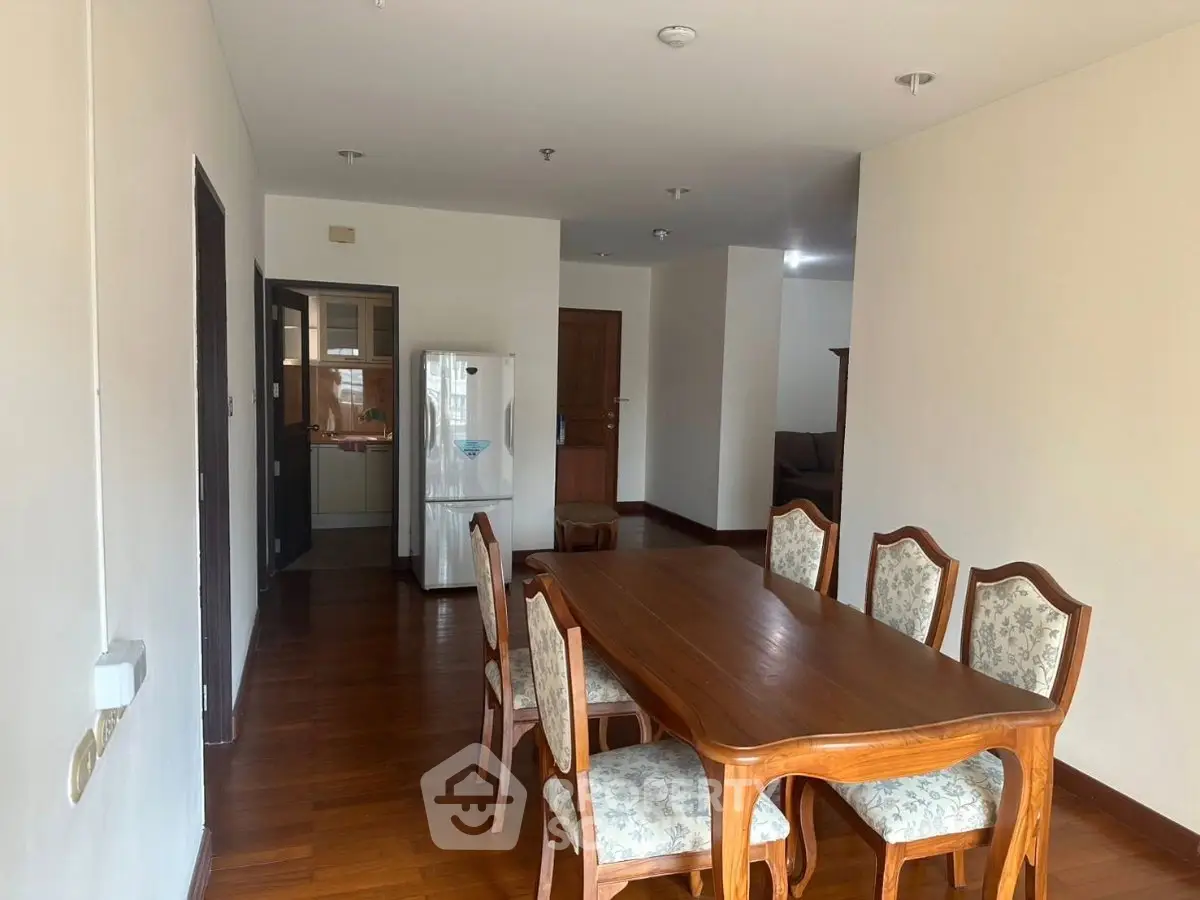 Spacious dining area with elegant wooden table and chairs, adjacent to a cozy living room and modern kitchen.
