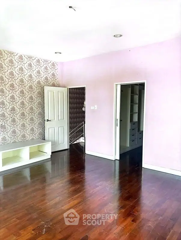 Spacious empty room with elegant wallpaper and wooden flooring