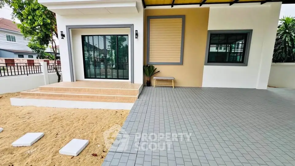 Modern house exterior with spacious tiled patio and large sliding glass doors.