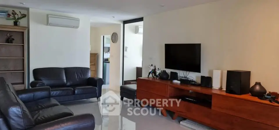 Spacious living room with modern leather sofas and sleek entertainment unit.