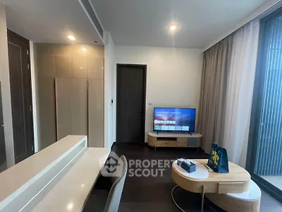 Modern living room with sleek furniture and large TV, featuring floor-to-ceiling windows.