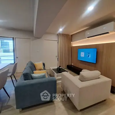 Modern living room with stylish furniture and wall-mounted TV, featuring cozy seating and elegant decor.