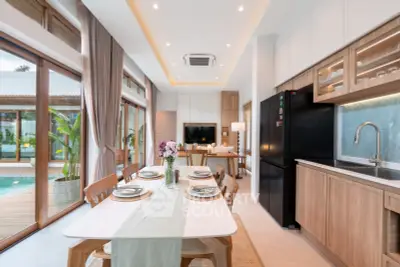 Luxurious open-plan kitchen and dining area with pool view, featuring modern appliances and elegant decor.