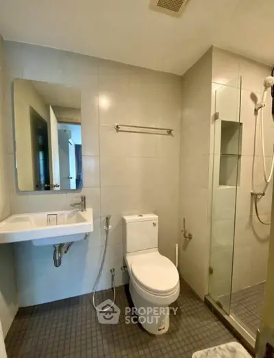 Modern bathroom with glass shower and sleek fixtures in contemporary apartment.