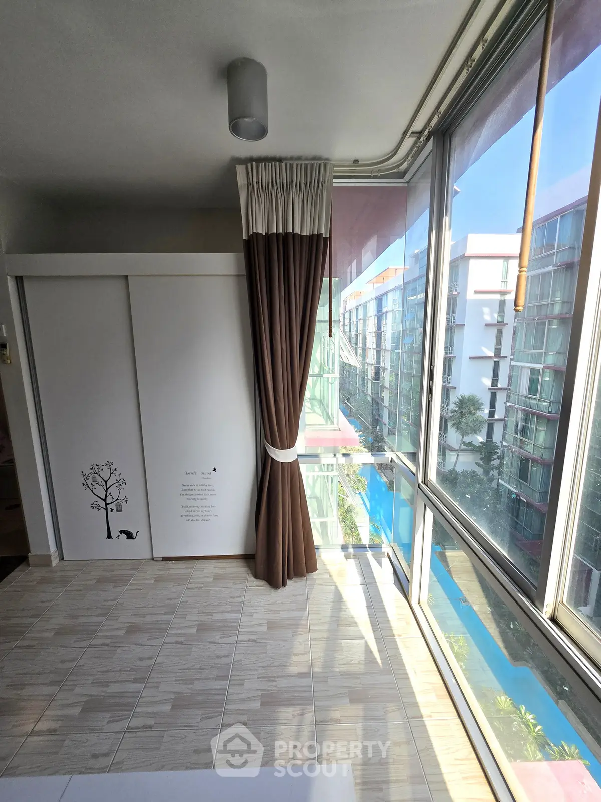 Bright corner unit with floor-to-ceiling windows offering a stunning view of the pool and modern architecture.