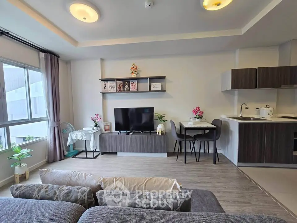 Modern living room with open kitchen, stylish decor, and ample natural light.