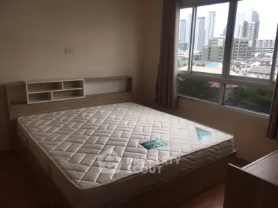 Spacious bedroom with large window offering city views and natural light.