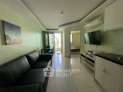 Modern living room with sleek black sofa, wall-mounted TV, and open layout leading to bedroom.