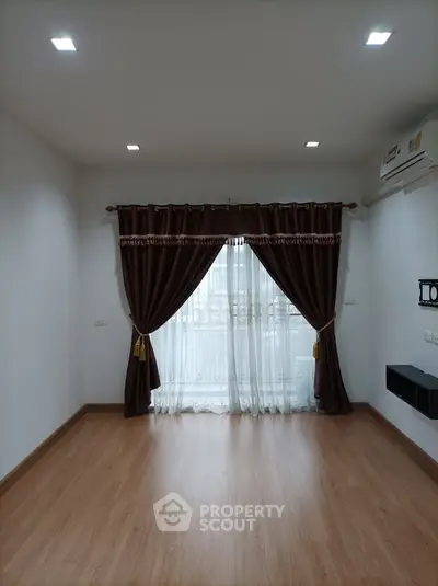 Spacious empty room with elegant curtains and wooden flooring, perfect for customization.