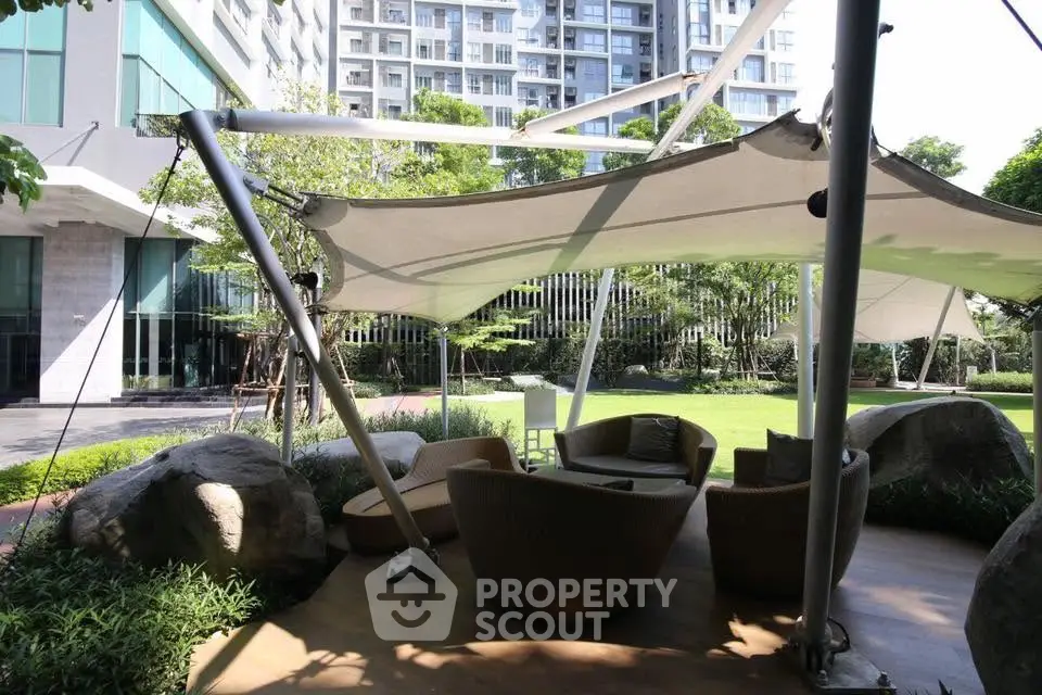 Luxurious outdoor seating area with modern canopy in upscale residential complex garden.