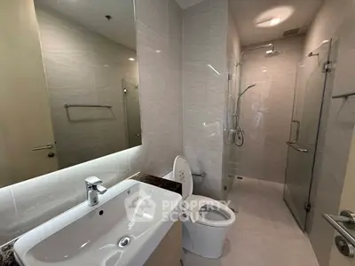 Modern bathroom with sleek fixtures and glass shower enclosure in a contemporary apartment.