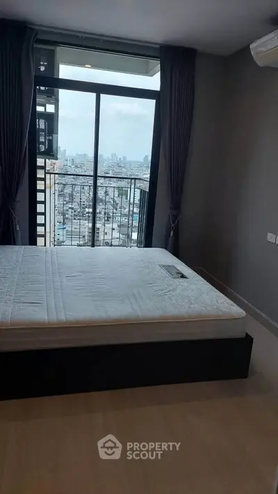 Modern bedroom with city view and balcony access in high-rise apartment