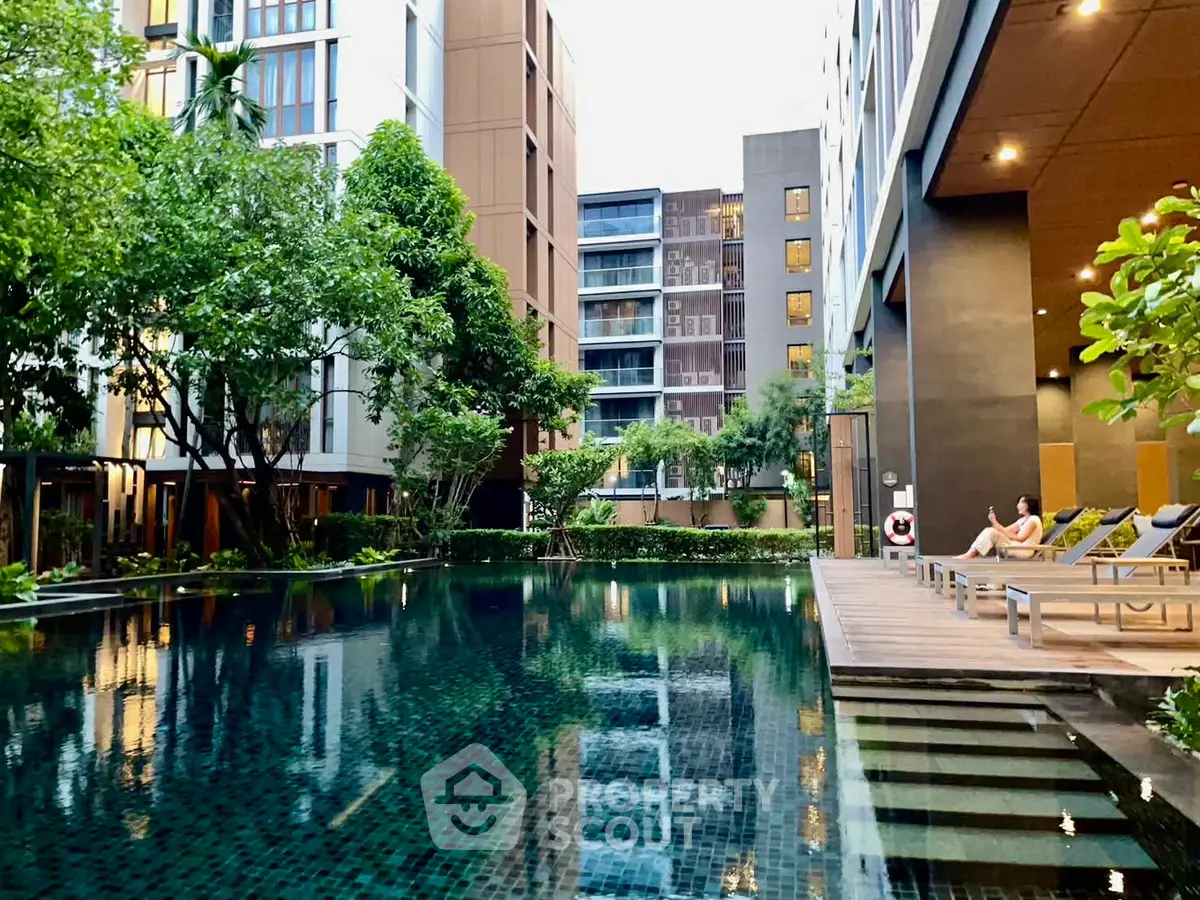 Luxurious condominium pool area with lush greenery and modern architecture.