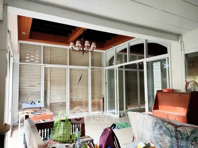 Spacious sunlit room with large windows and elegant chandelier, perfect for a cozy living area.