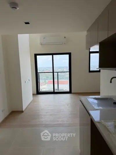 Modern apartment interior with open kitchen and stunning city view from large window.