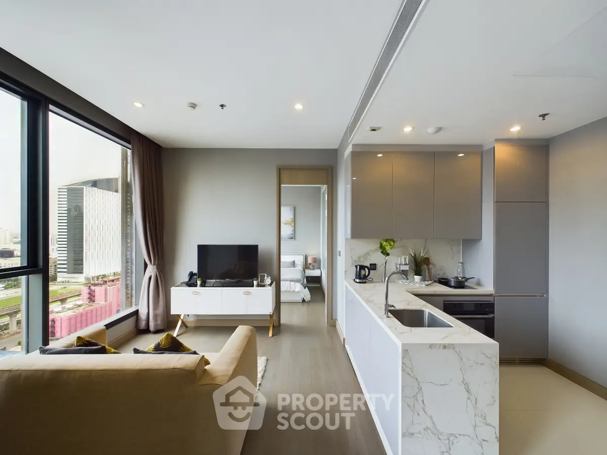Modern open-layout living room with kitchen, featuring sleek design and city view.